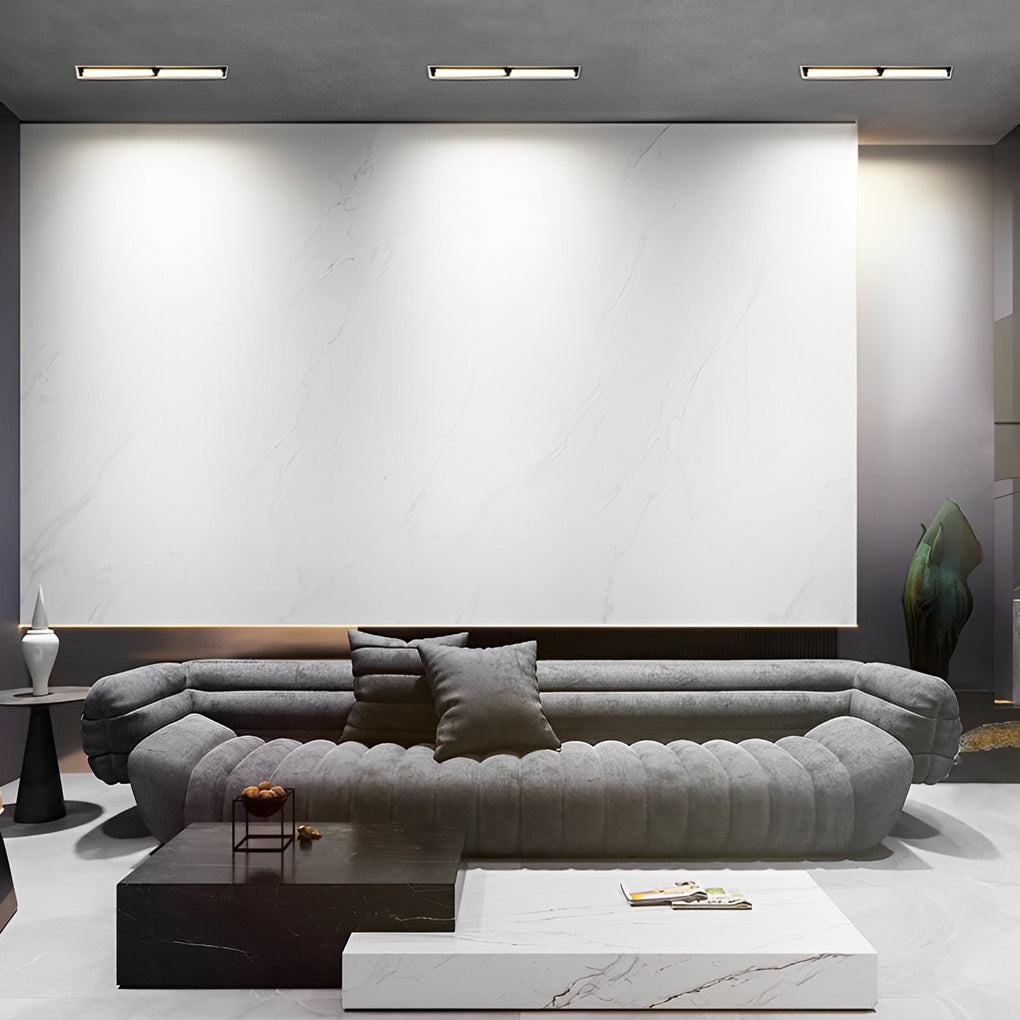 Recessed linear light fixtures installed in a modern living room ceiling
