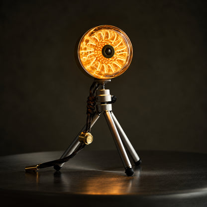 Donut Glow brass rechargeable lamp glowing on a compact tripod.