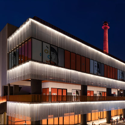 Linear LED wall washer illuminating a modern building entrance with vertical metal paneling.
