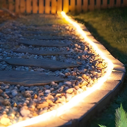 Outdoor embedded LED light strips providing warm light along a stone pathway.
