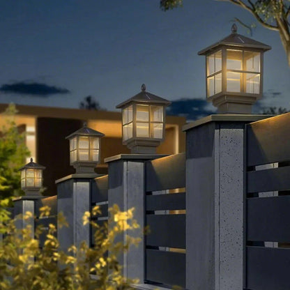 Stone light pillar with a black lantern, providing soft light near a garden.