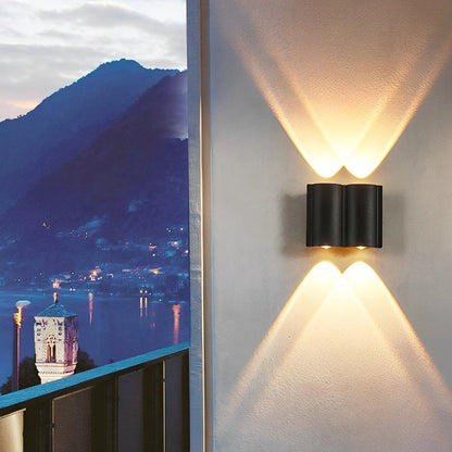 Up and down outdoor wall lights casting warm glow on balcony with scenic lake and mountain view at dusk.
