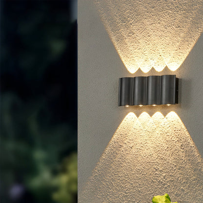 Up and down outdoor wall lights highlighting modern house facade with warm light beams at night.